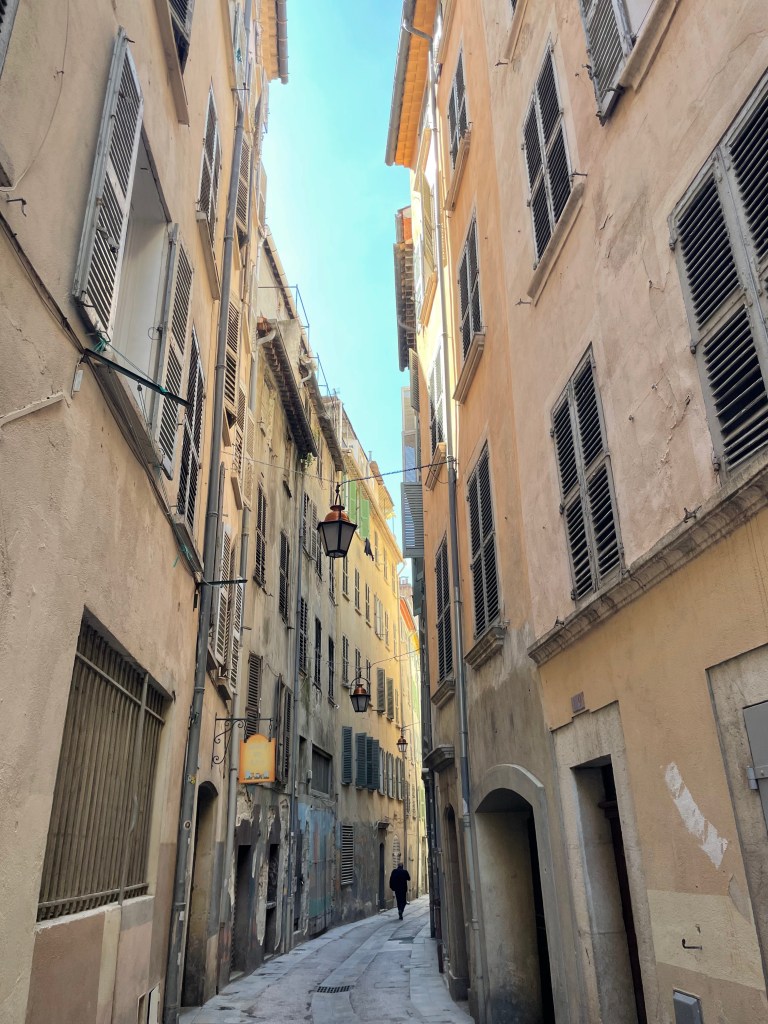 Úzká ulice v Toulonu s historickými budovami a modrou oblohou.